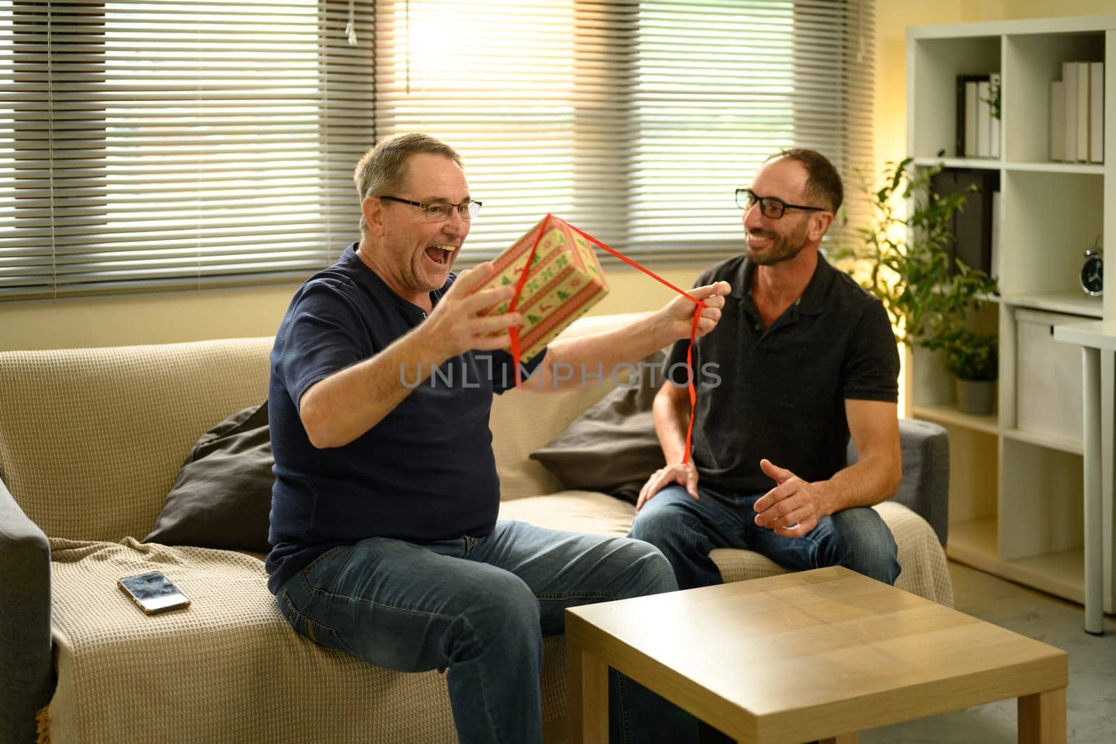 Happy father receiving a surprise present from his son. Father day concept.
