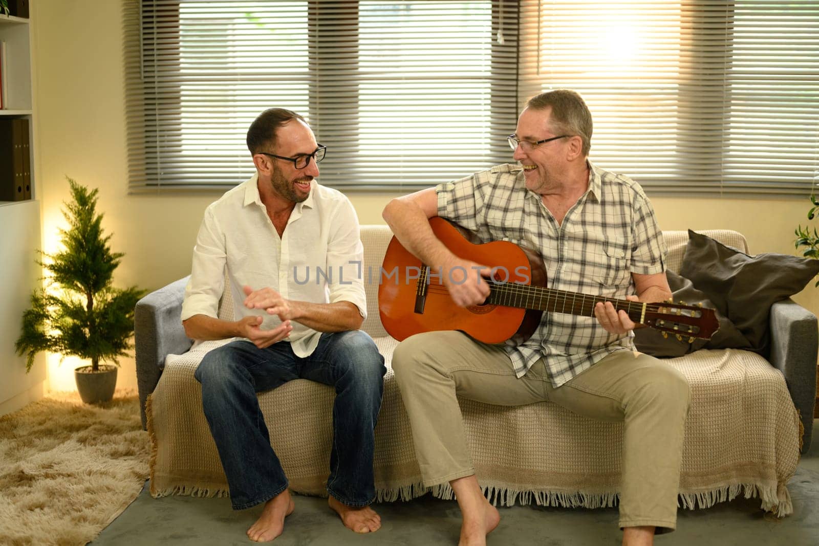 Father and adult son bonding over music, enjoying quality time with acoustic guitar. Father day concept.