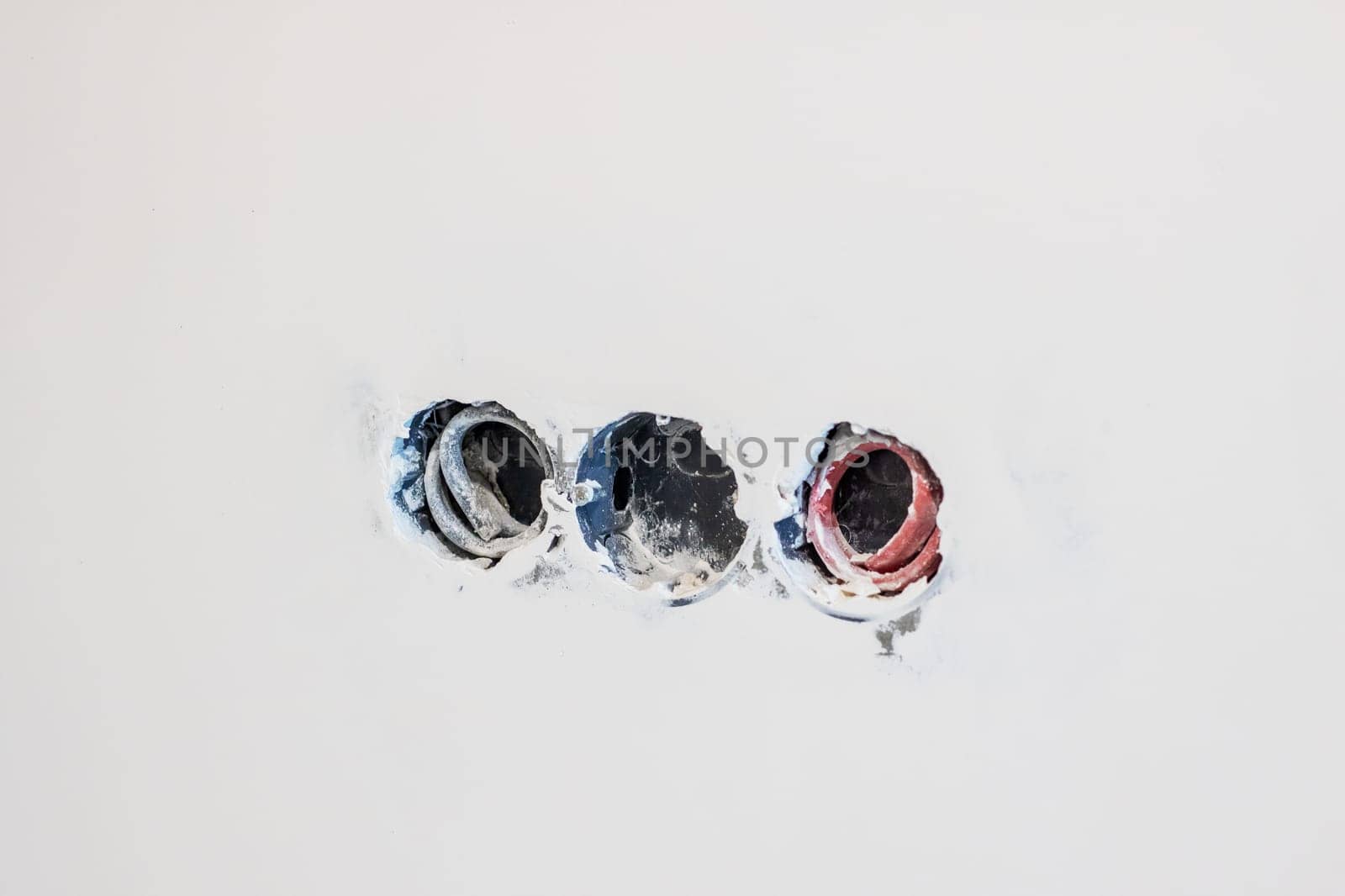 This is a minimalist image that depicts three circular holes on a textured wall, emphasizing both form and color