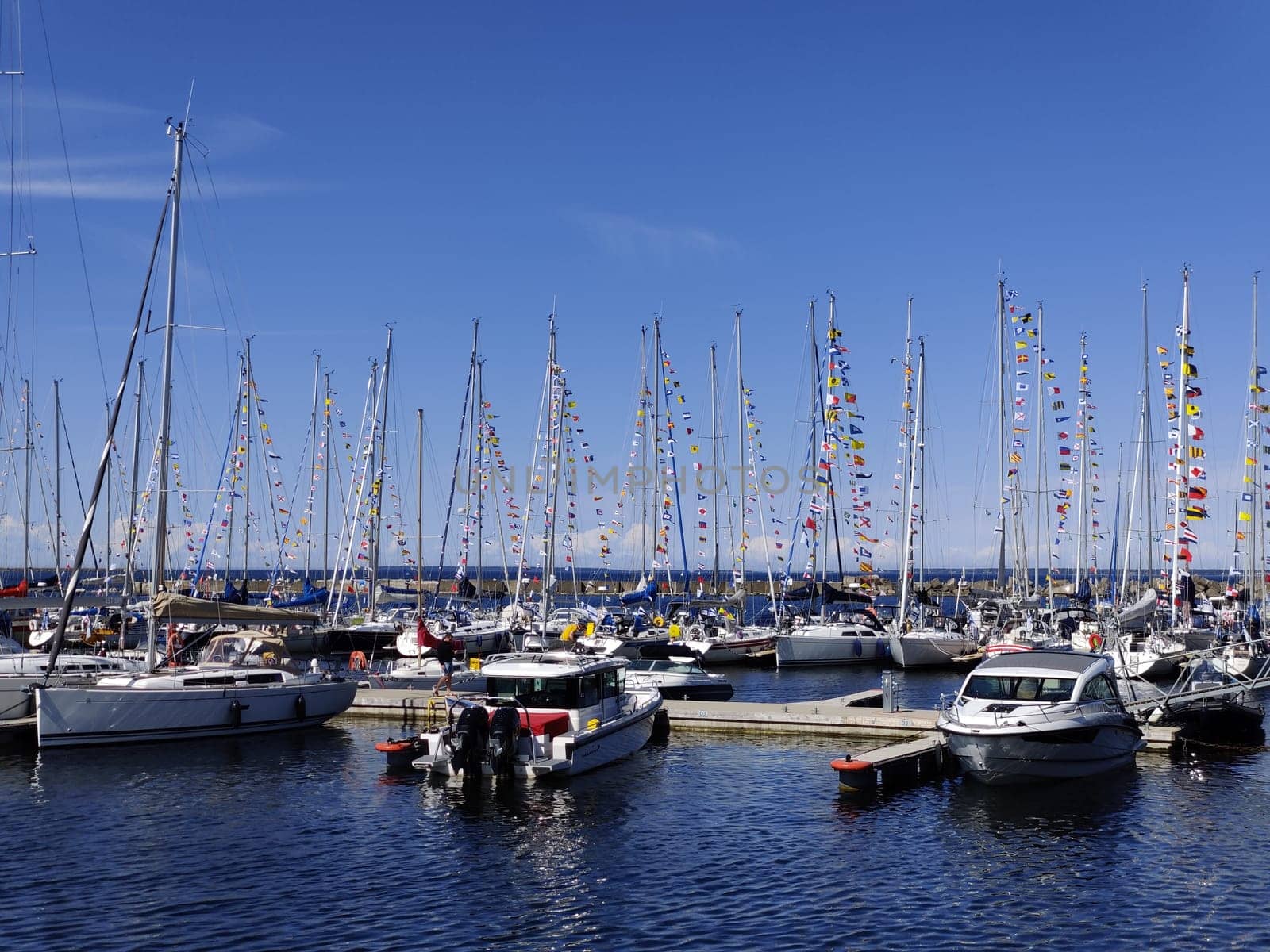Tallinn, Estonia - MAY 30, 2025: A festive scene at a harbor in Tallinn, Estonia, where multiple sailboats are moored and decorated with colorful signal flags
