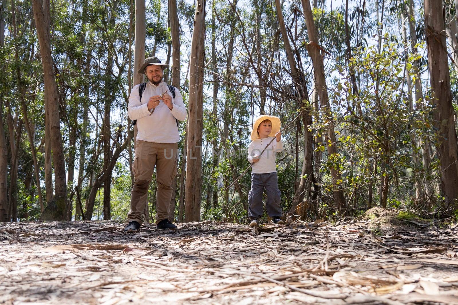 Father and son wearing straw hats enjoying a sunny day in a eucalyptus forest