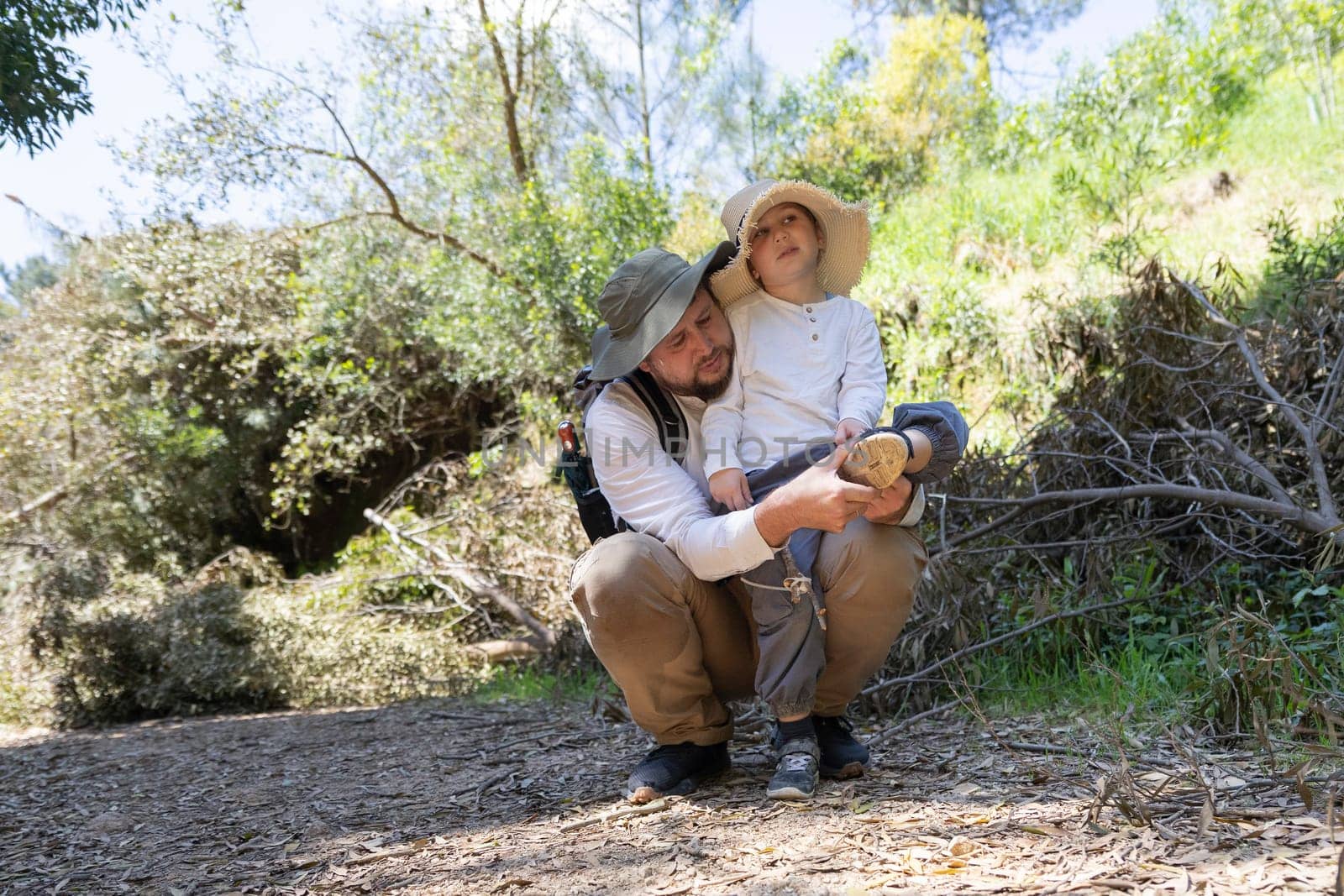 Father and son taking a break during a hike in the woods, removing hiking shoes
