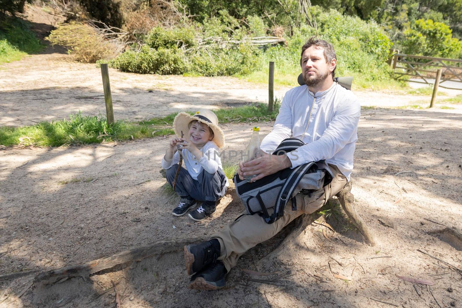Father and son taking a break during a hiking trip, enjoying the peaceful surroundings
