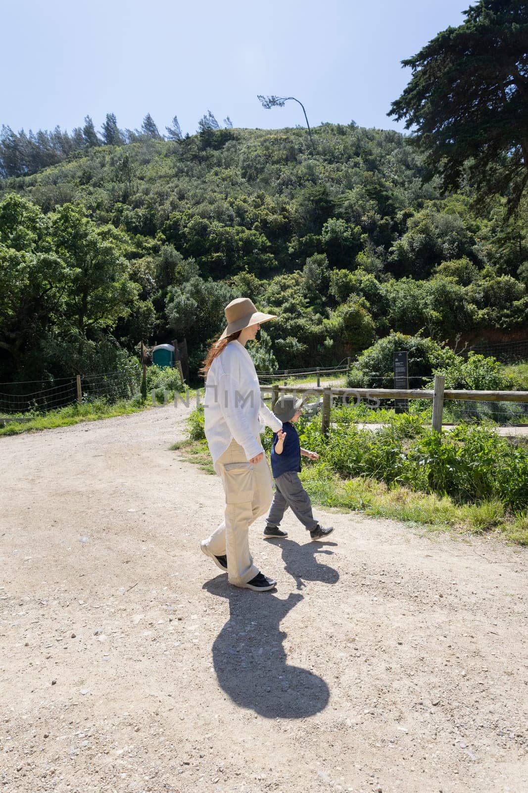 Mother and son enjoying a leisurely stroll on a sunny day, surrounded by the beauty of nature