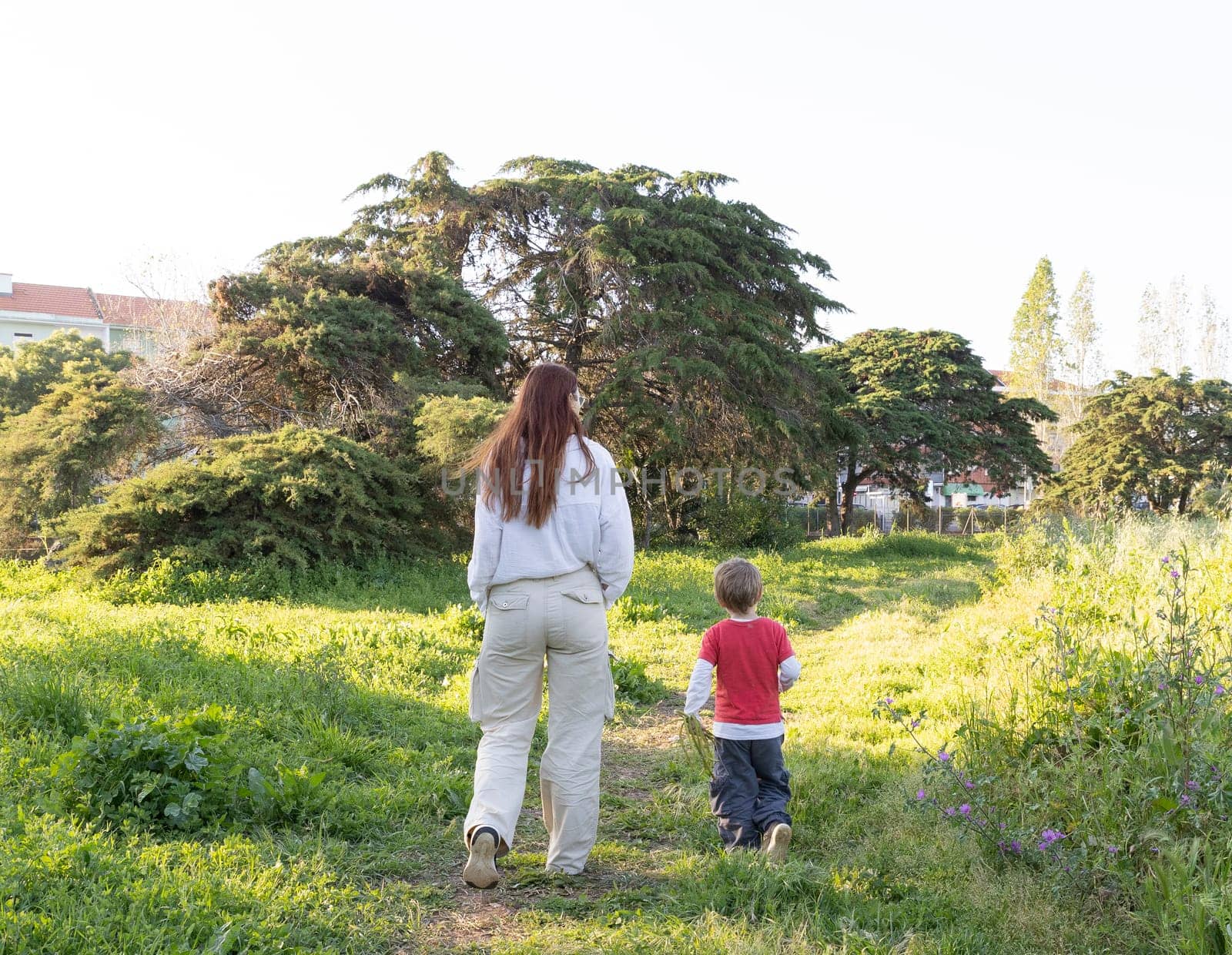 Mother and son enjoying a peaceful walk through nature, surrounded by lush greenery and trees