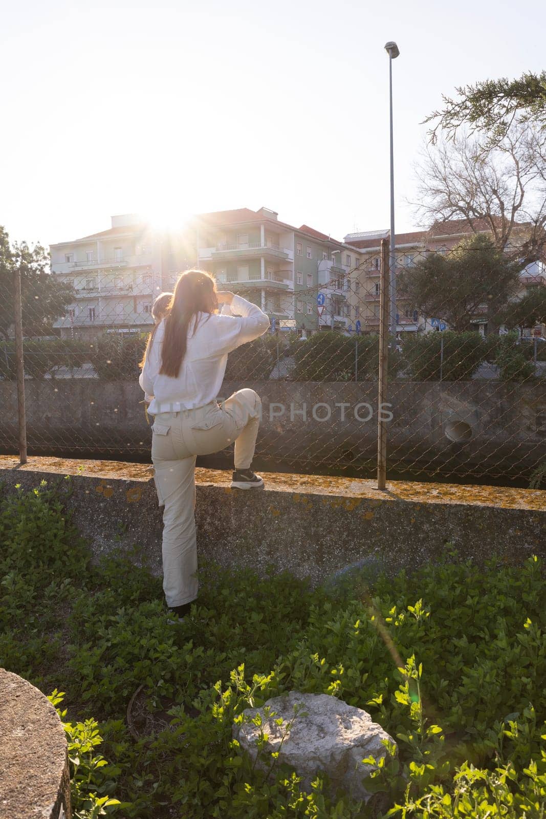 Young mother holding her baby shielding her eyes from the setting sun in an urban environment