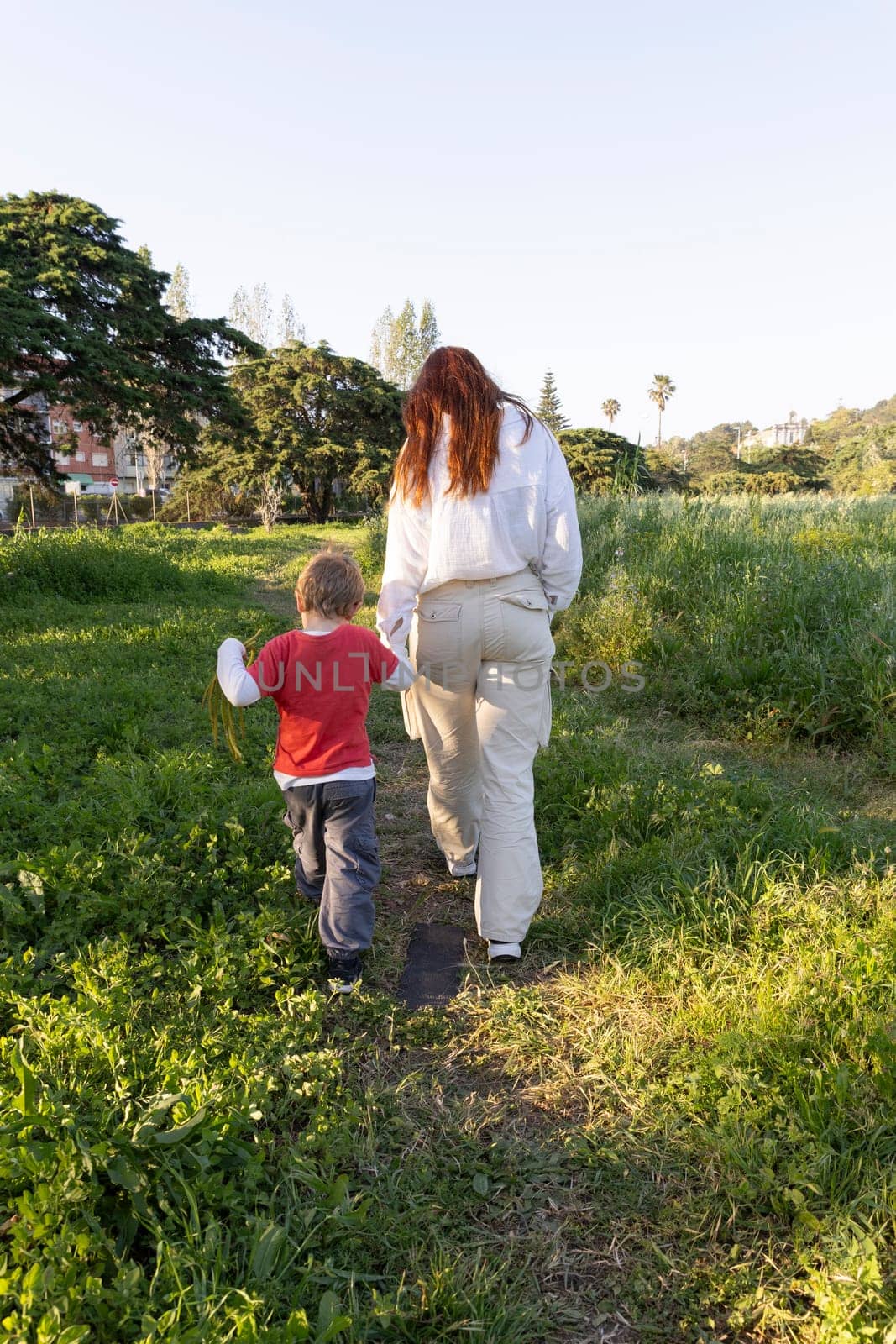 Mother and son enjoying a leisurely stroll through a vibrant green meadow, creating cherished memories amidst nature's embrace