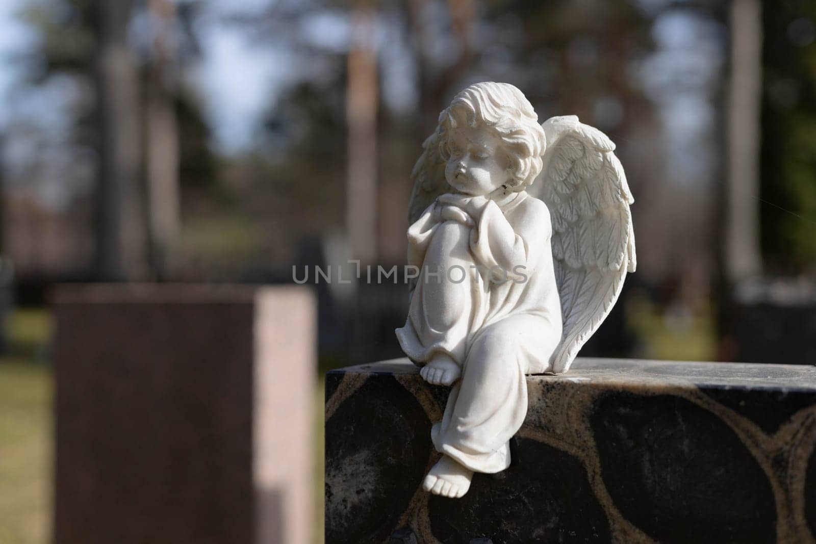 A peaceful Lutheric cemetery in Finland, featuring a solitary grave marked by a stone angel. The surroundings are calm and reflect a quiet, respectful atmosphere
