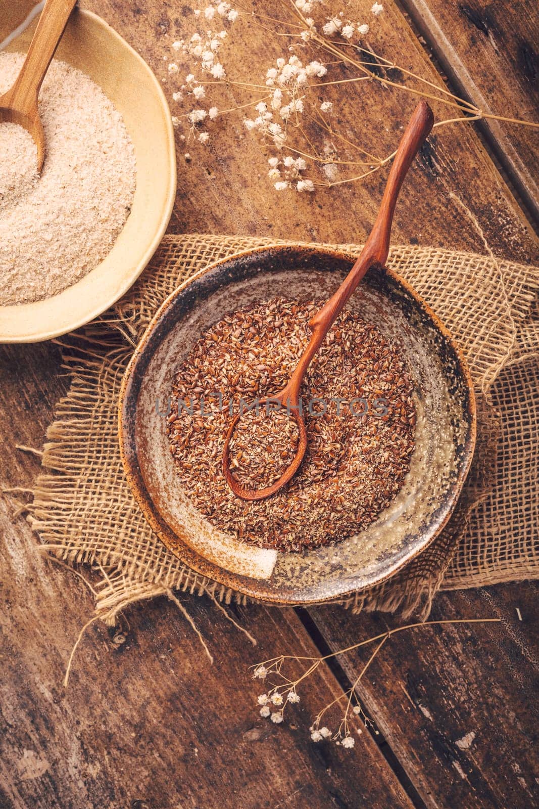 Shredded flax seeds and heap of psyllium husk (Isabgol) in a bowl on wooden table