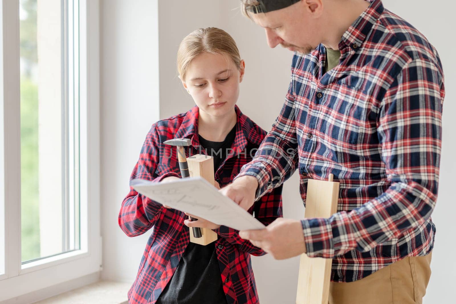 Dad And Daughter Looking At Furniture Assembly Diagram At Home
