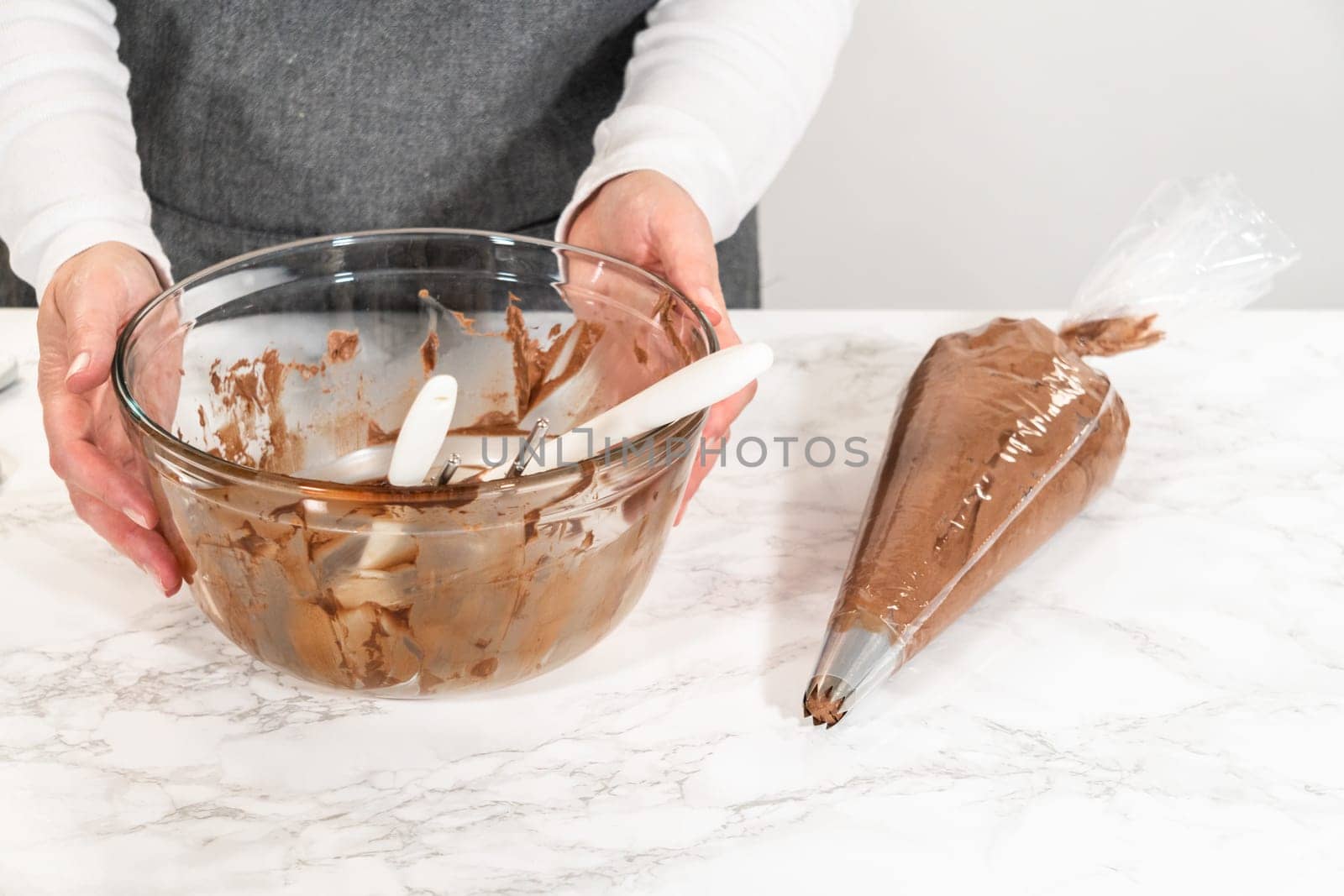 The chocolate icing is carefully transferred into a piping bag, ready to adorn the scrumptious cupcakes.