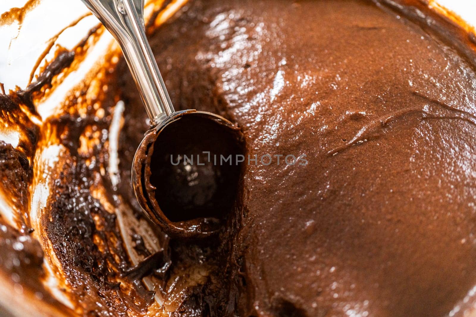 The process involves carefully scooping the rich batter into the waiting cupcake pan.