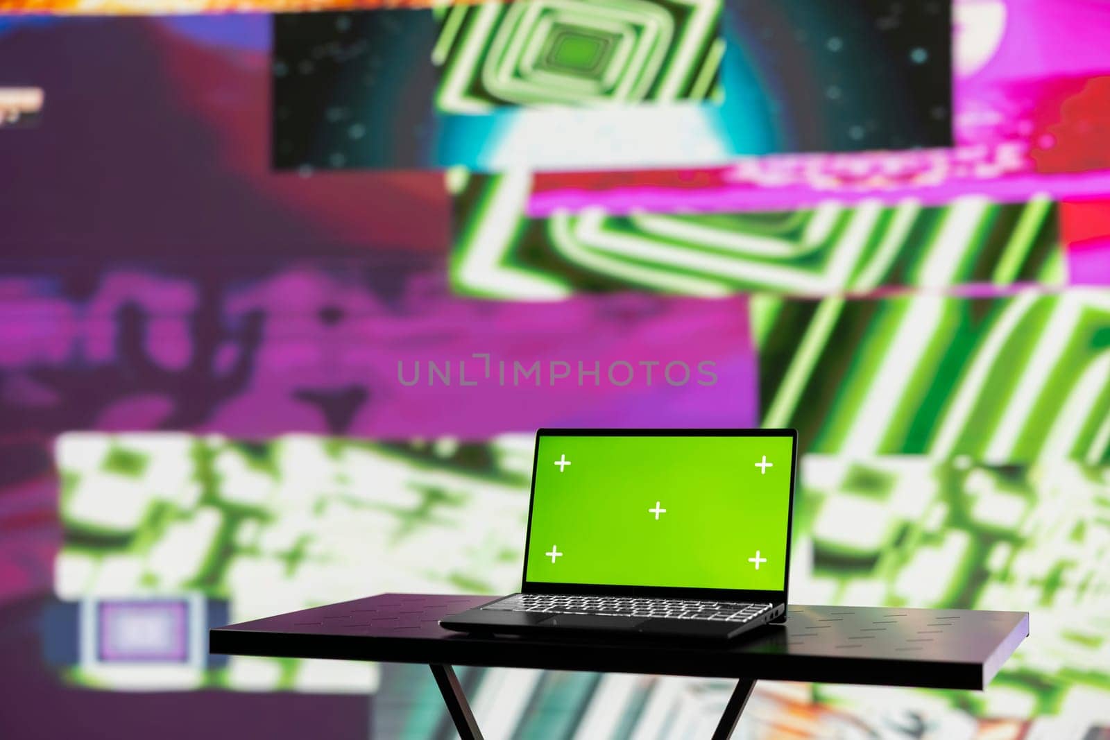 Wireless pc running chroma key display surrounded by colorful visual art clips, glowing in the dark and showcasing a clubbing atmosphere. Nightlife ambiance with urban lights and vibes.