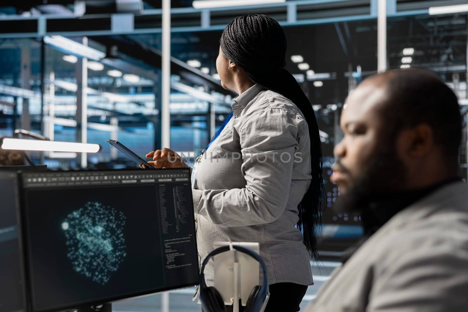 Data center employee monitoring system performance using PC, identifying malfunctions. African american server farm IT expert troubleshooting computer bugs, implementing optimizations