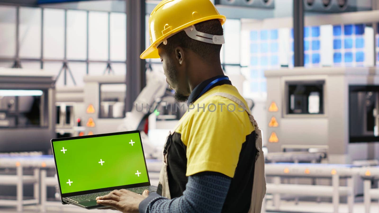 Engineer in smart factory using green screen laptop to analyze IoT sensors data. Industry 4.0 plant expert performing system diagnostics on chroma key mockup notebook to reduce downtime, camera B