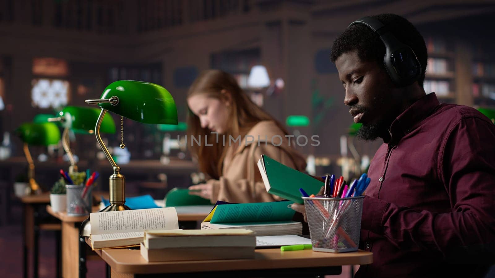 Black guy using study music to help with deep focus for academic success, consulting the campus university database to find reliable sources. Male college student fights for diploma. Camera A.