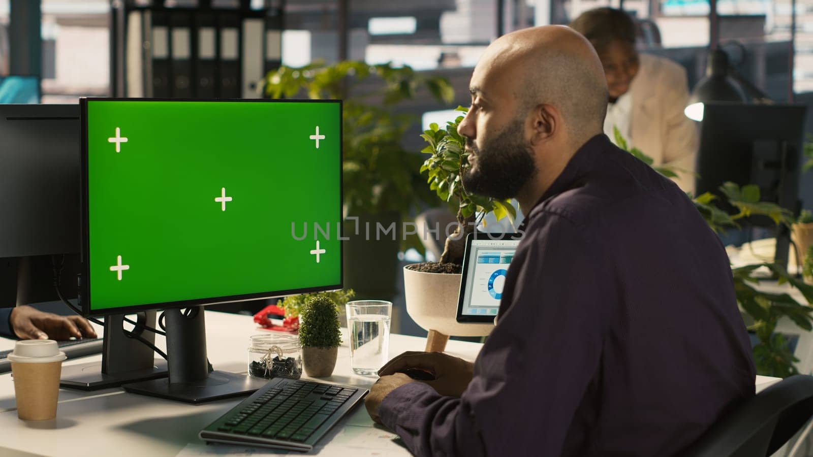 Employee at work using isolated screen PC to check progress done on customer commissioned project. Office clerk in front of mockup computer reading data statistics on paperwork after audit, camera A