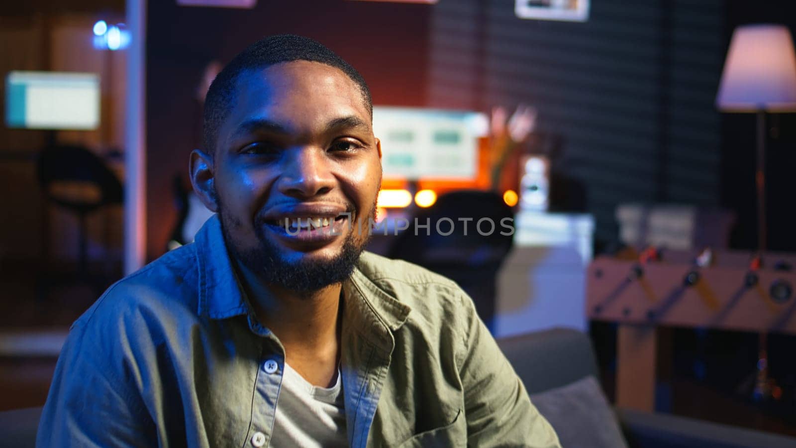 Portrait of african american person smiling and working in his living room, using laptop to solve remote freelancing tasks as a self employed guy. Young adult feels relaxed at home. Camera A.