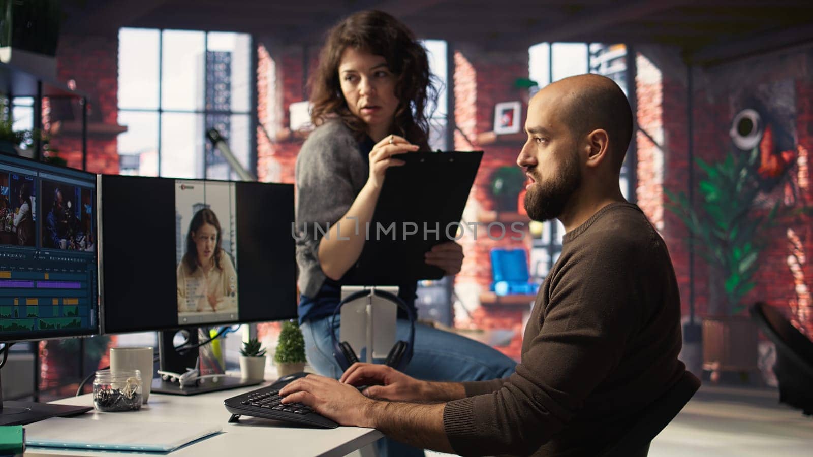 In professional production office, team discusses content strategy and trends while reviewing footage on computers, aiming to increase followers and viral potential across platforms. Camera A.