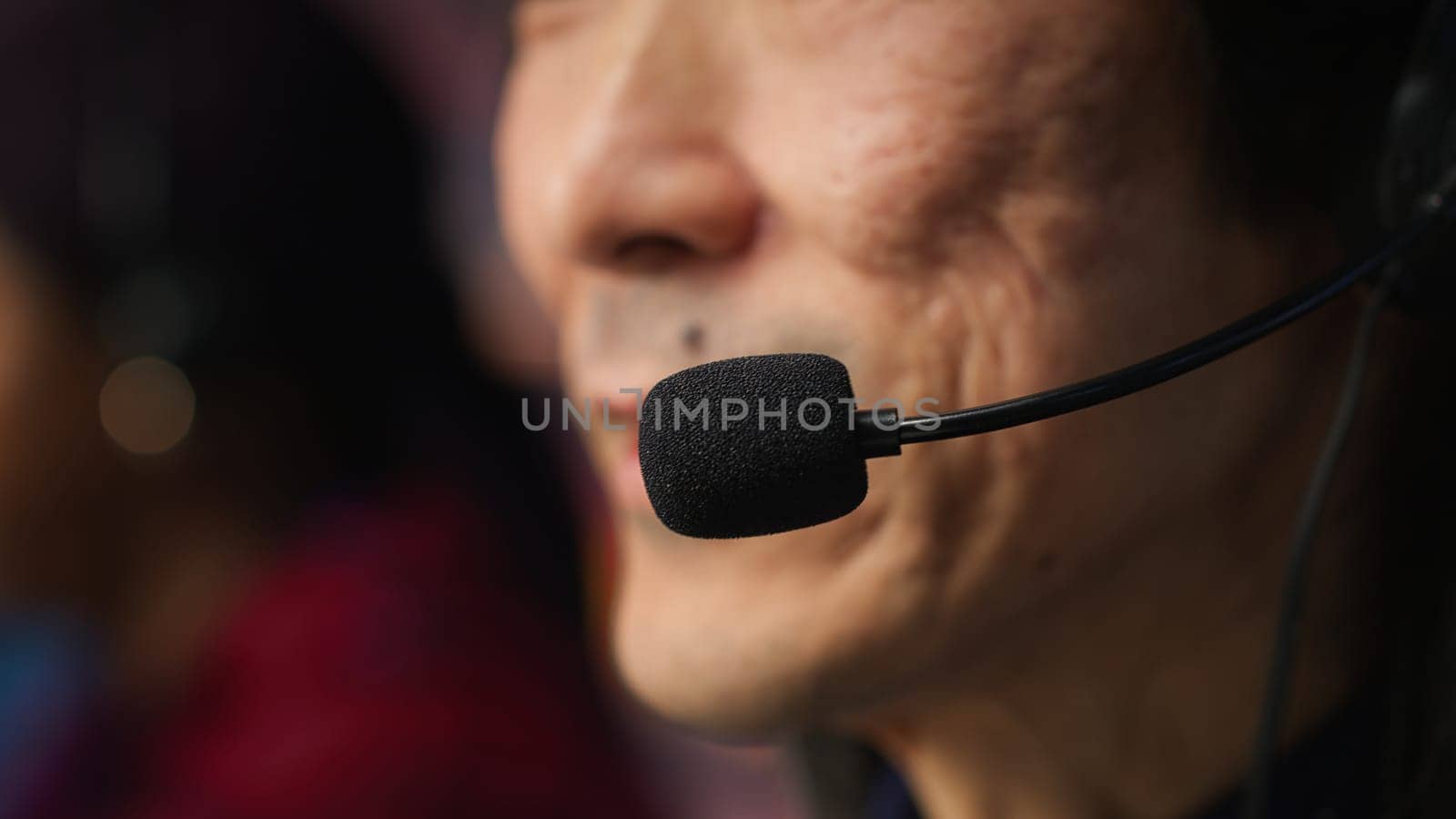 Closeup of experienced worker talking with customer using headphones mic to gain new sales. Asian account manager in office using audio headset, speaking with client to generate leads, camera A