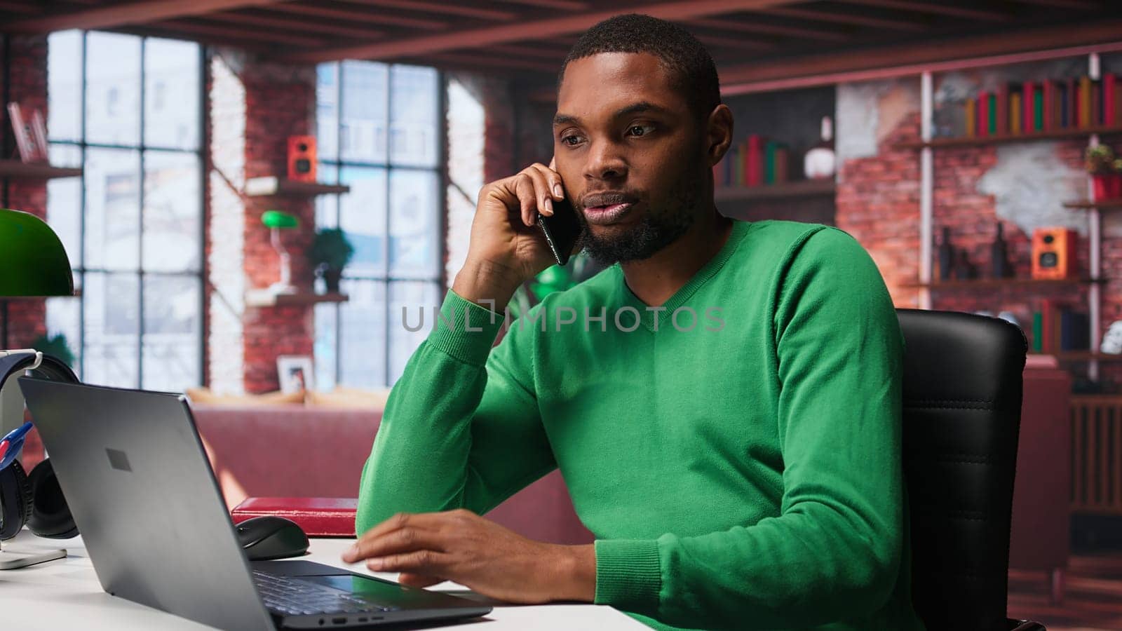 Smiling man at home having friendly conversation with friends over phone call on smartphone. African american guy having fun catching up with people on telephone line, freelance. Camera B.