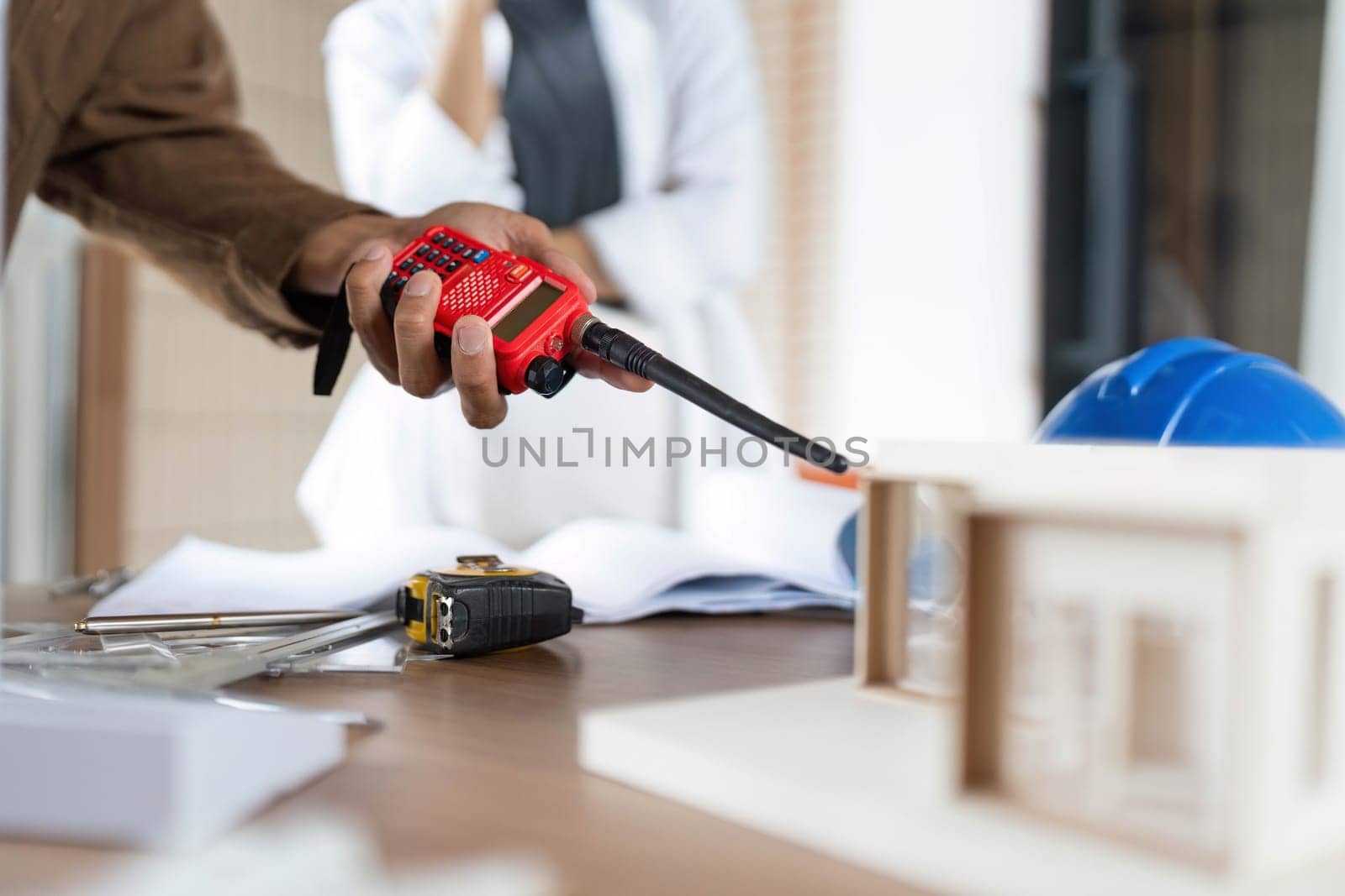 An architect using a walkie-talkie to manage a construction project, focusing on ESG principles and efficient communication.