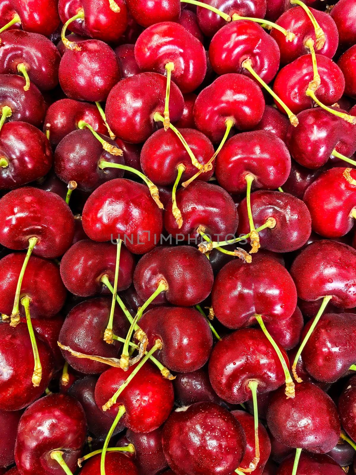 Freshly harvested ripe cherries piled closely together, showcasing their vibrant red color and texture.