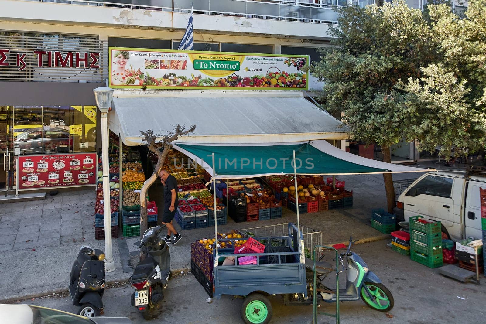Rodas.Greece - june 06, 2025:  Bustling open-air fruit and vegetable shop on a Rhodes street, Greece, showcasing a wide variety of fresh produce, a local vendor, and authentic ambiance.