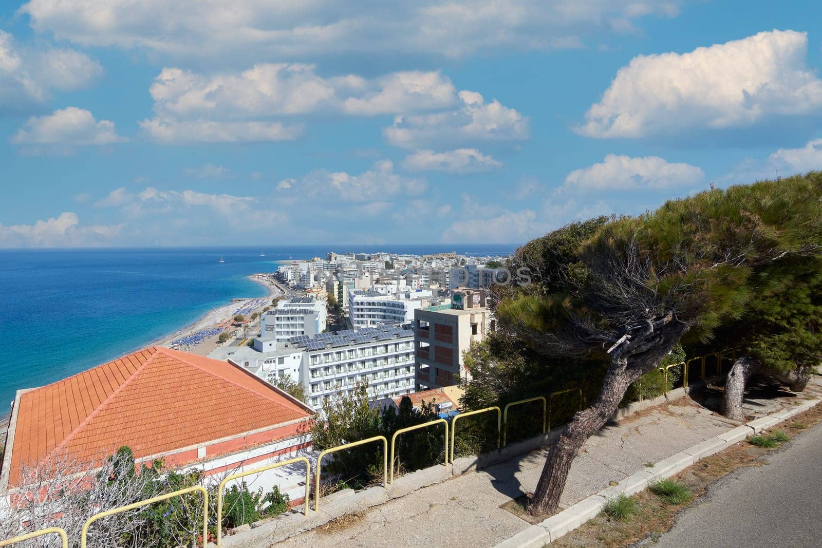 Rhodes. Greece - June 06, 2025: Elevated perspective of Rhodes beach, showing the extent of the coastline and city buildings. The contrast of the blue sea and sky with the sand.
