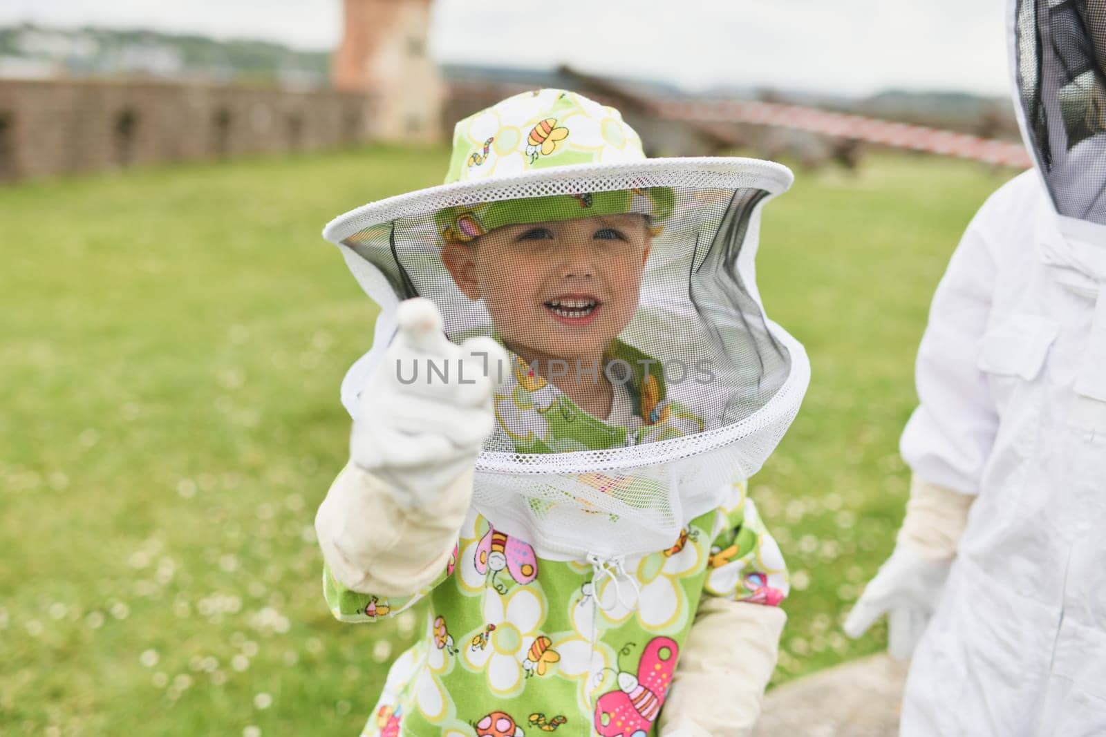 A beekeeper child in apiary in a protective suit