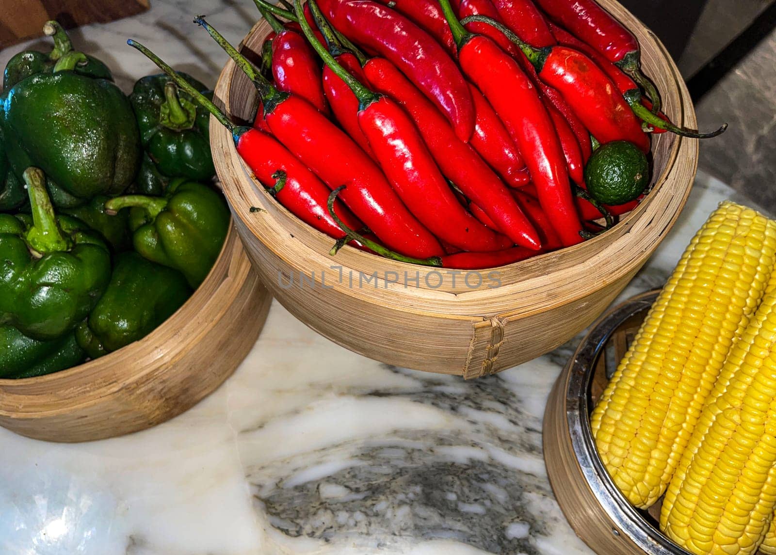 Vibrant red chili peppers and fresh green bell peppers arranged in bamboo bowls creating a colorful display perfect for food themes, cooking, healthy eating, and agricultural or culinary content.