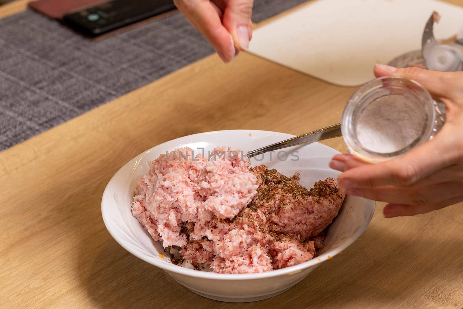 Just ground meat mince in the glass bawl of the electrical chopper on the kitchen counter top being seasoned and mixed. Cooking