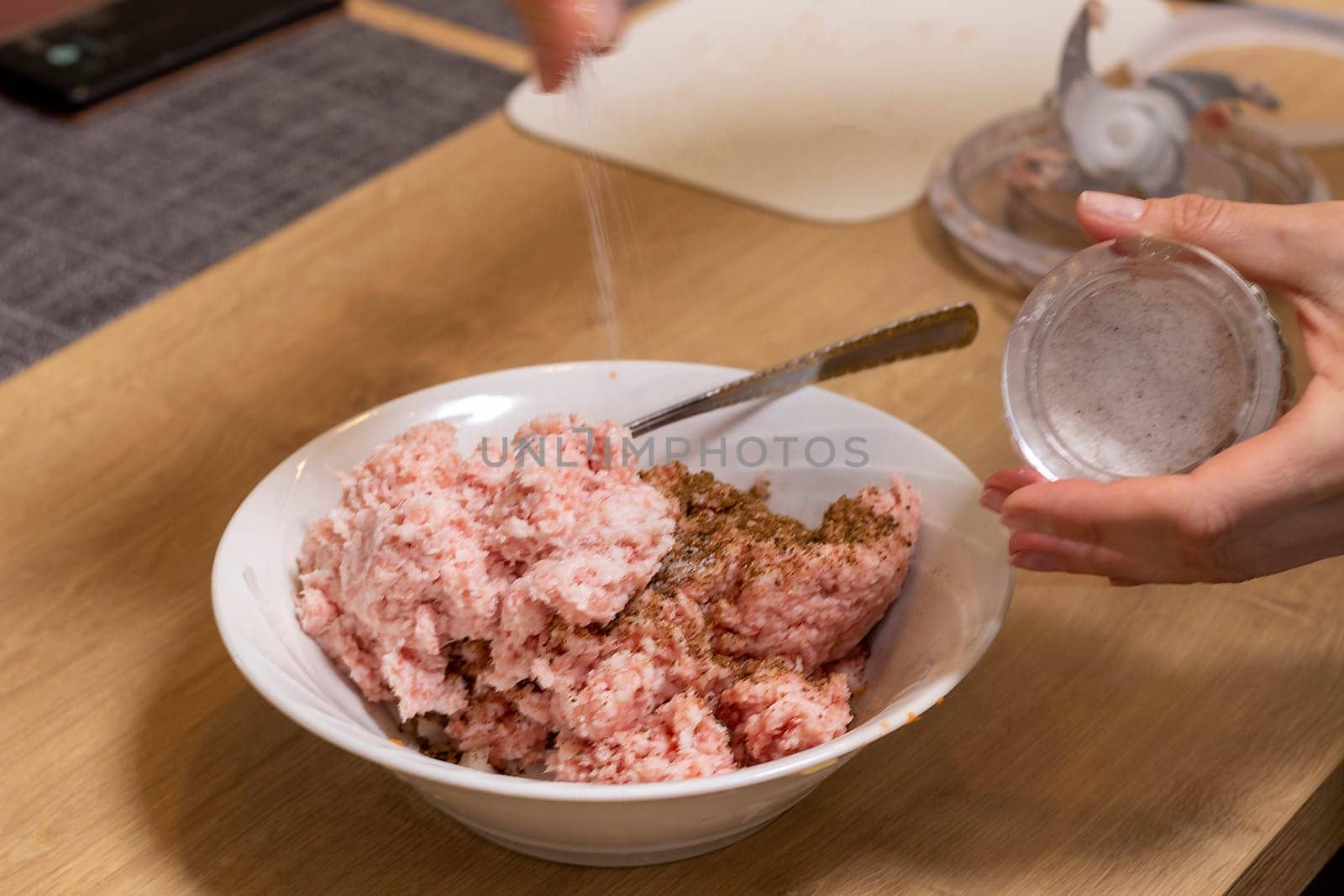 Just ground meat mince in the glass bawl of the electrical chopper on the kitchen counter top being seasoned and mixed. Cooking