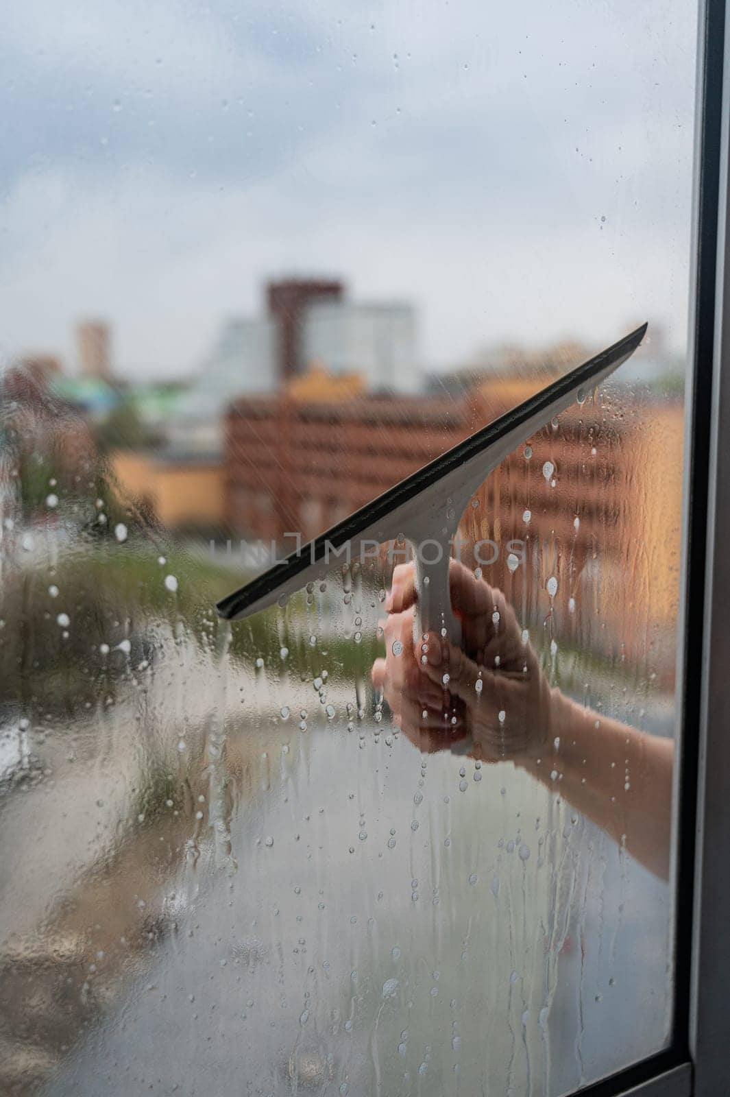 A woman washes a window with a scraper