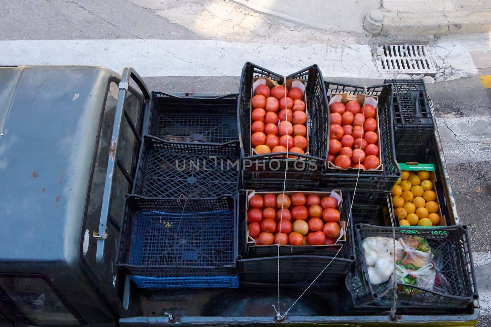 Overhead view of the back of a truck loaded with crates of ripe tomatoes, citrus, and other fresh produce