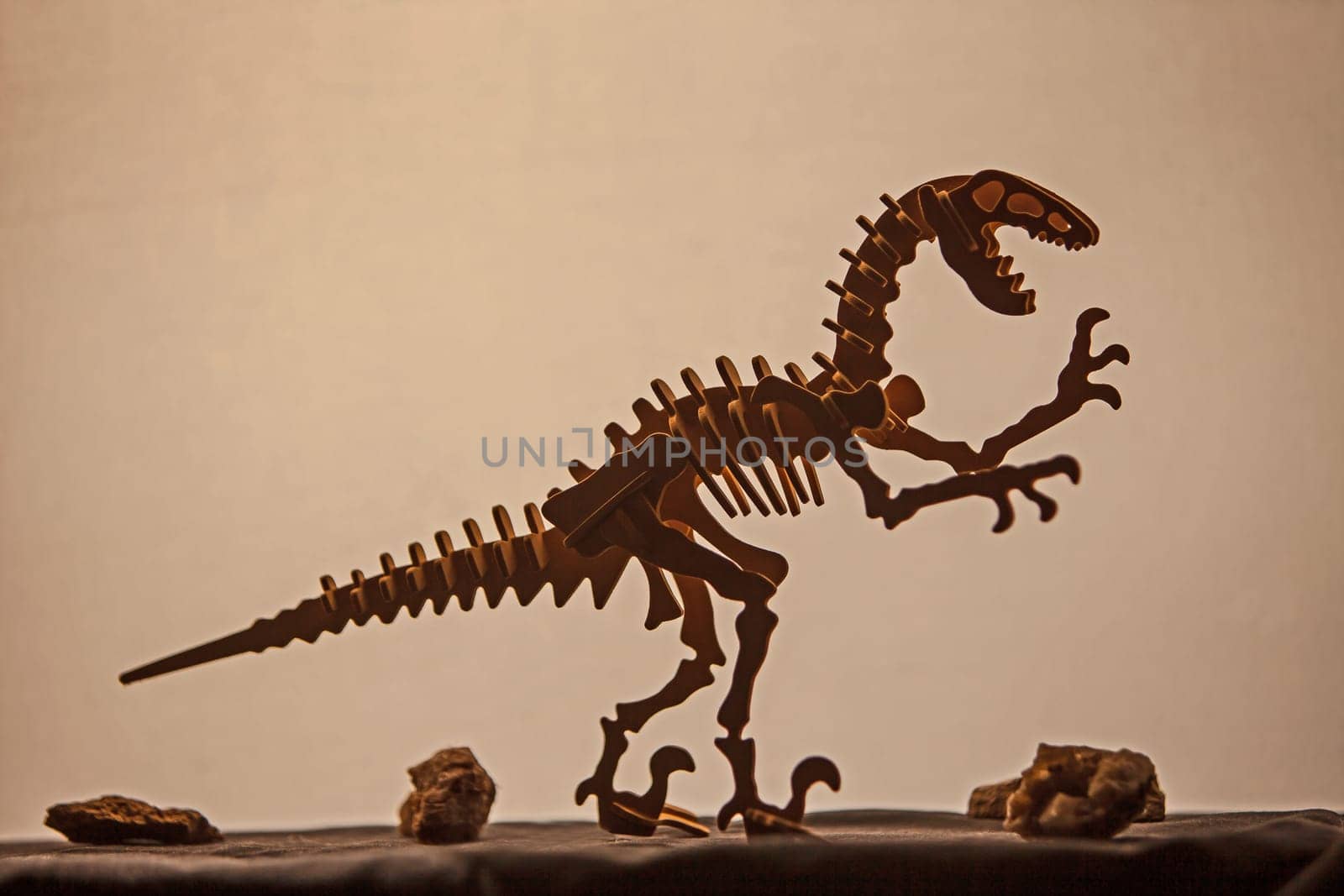 Wooden model of a Velociraptor silhouetted against a light background