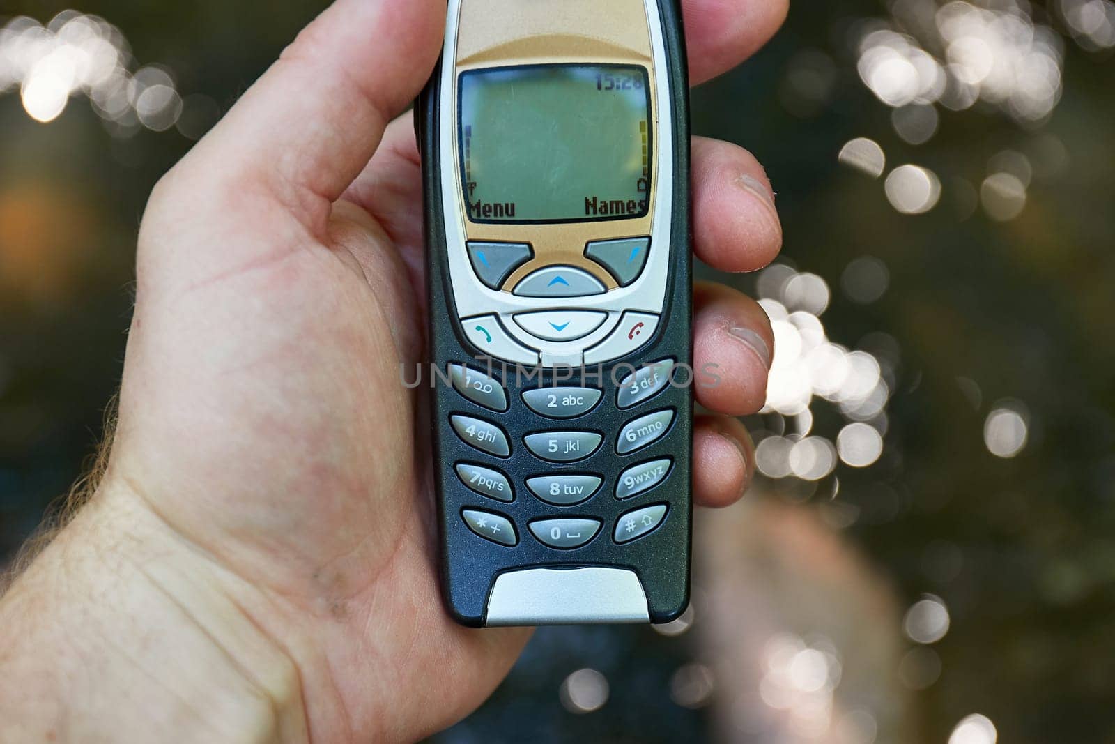 Cell phone in used condition held above the water surface of a fresh forest stream.