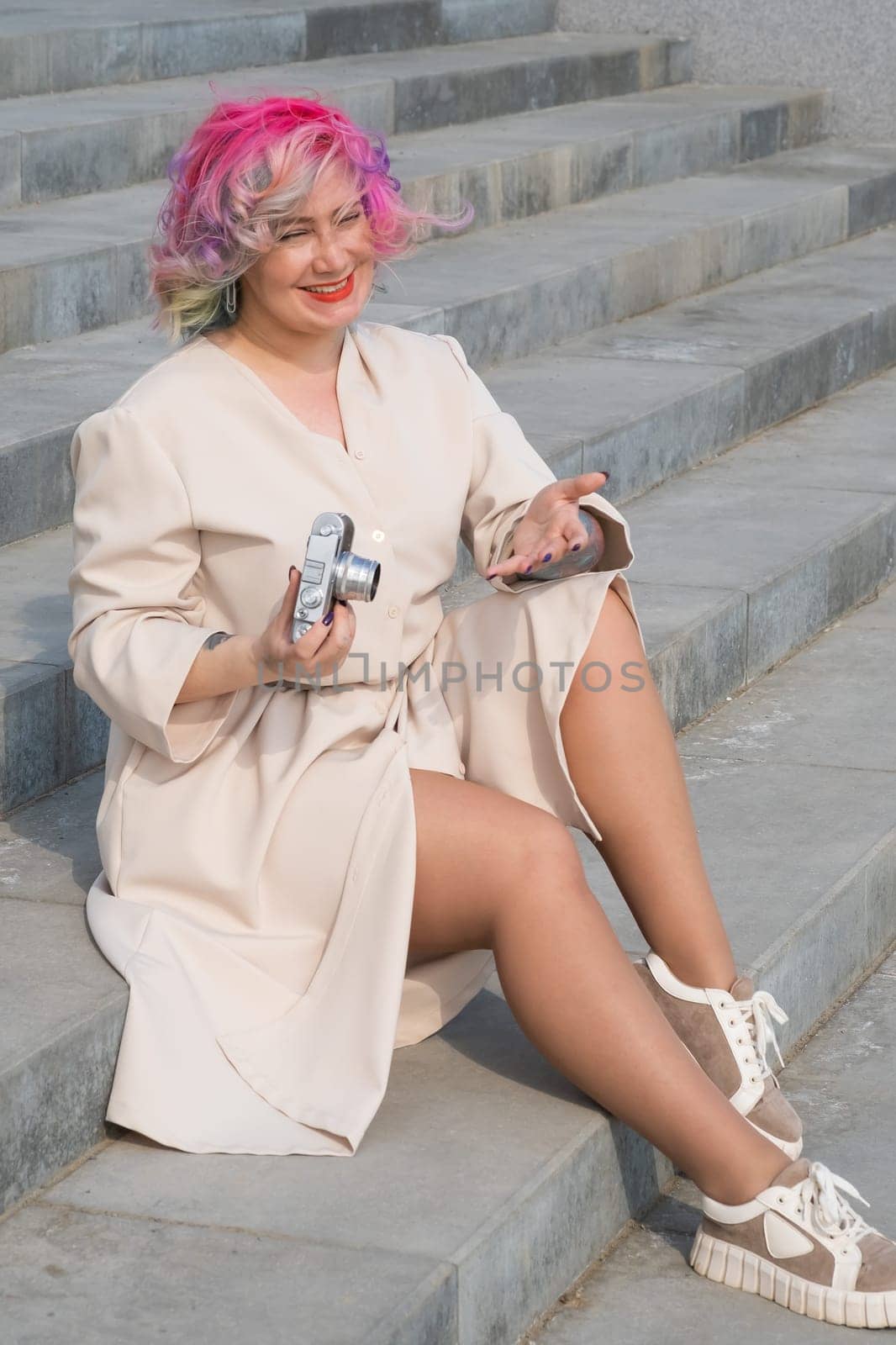 Caucasian woman with curly colored hair takes pictures on an old retro camera outdoors.
