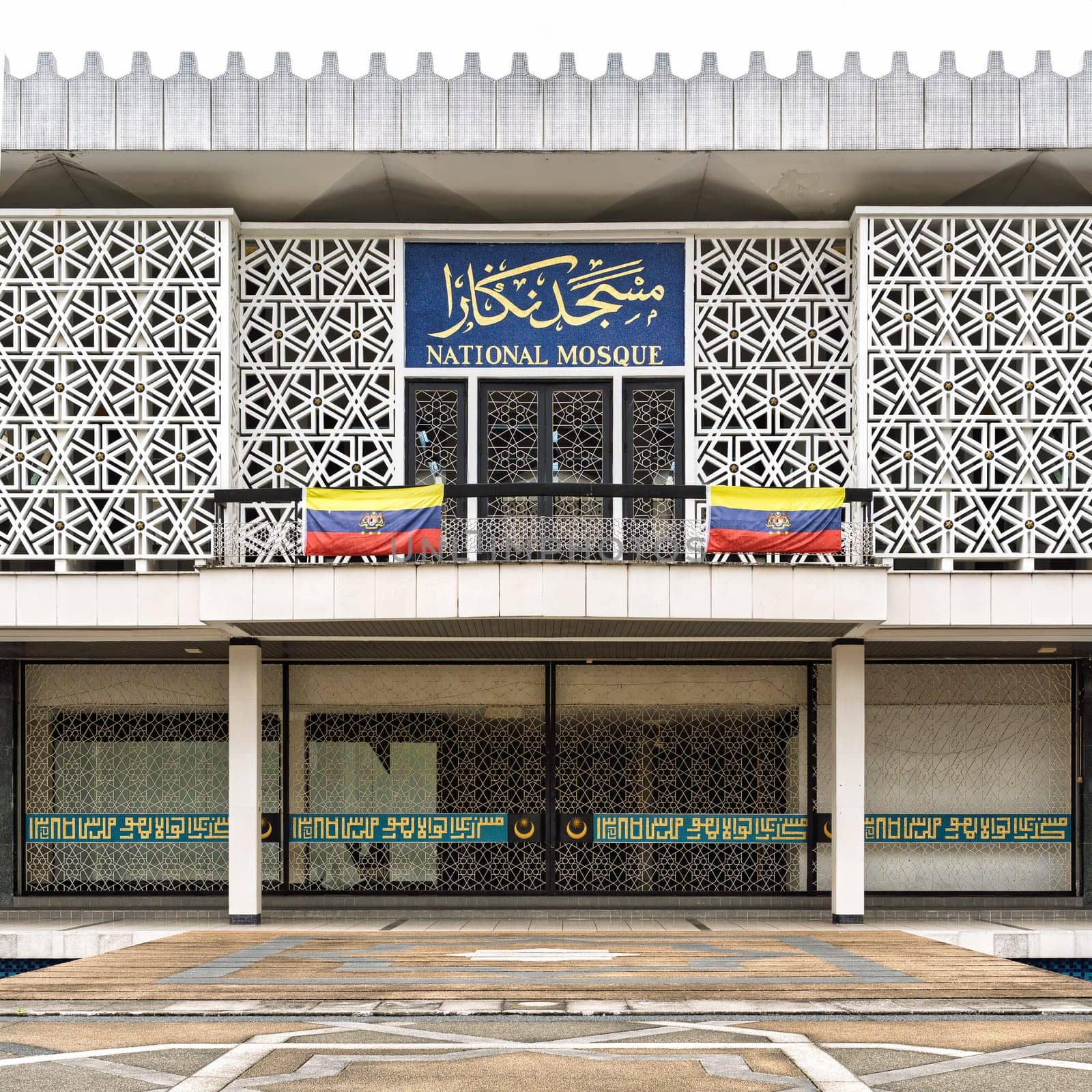 Facade of the National Mosque (Masjid Negara) with Malaysian flags, a modern Islamic architectural landmark in Kuala Lumpur, Malaysia