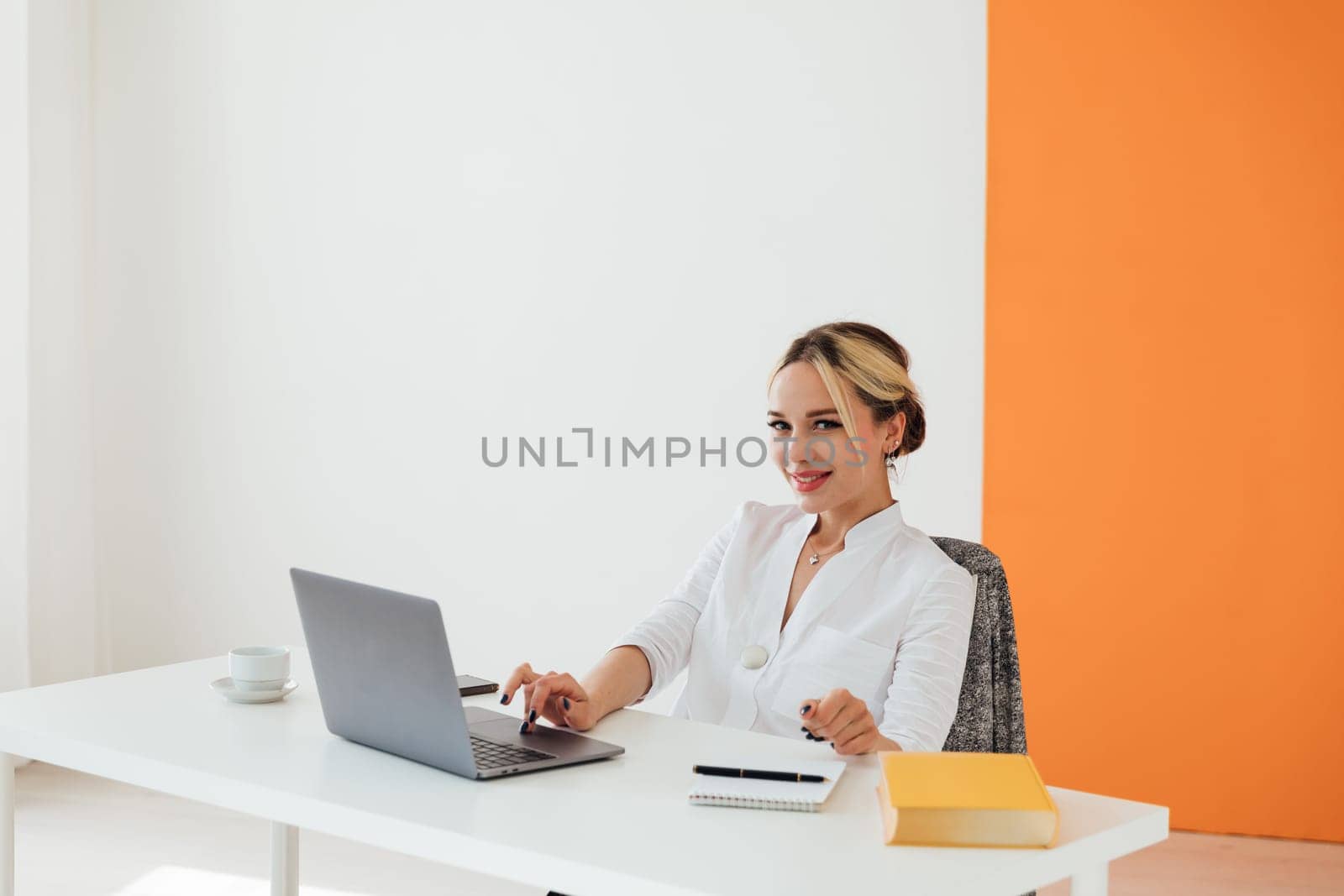 Business woman sitting at office desk and working on laptop online