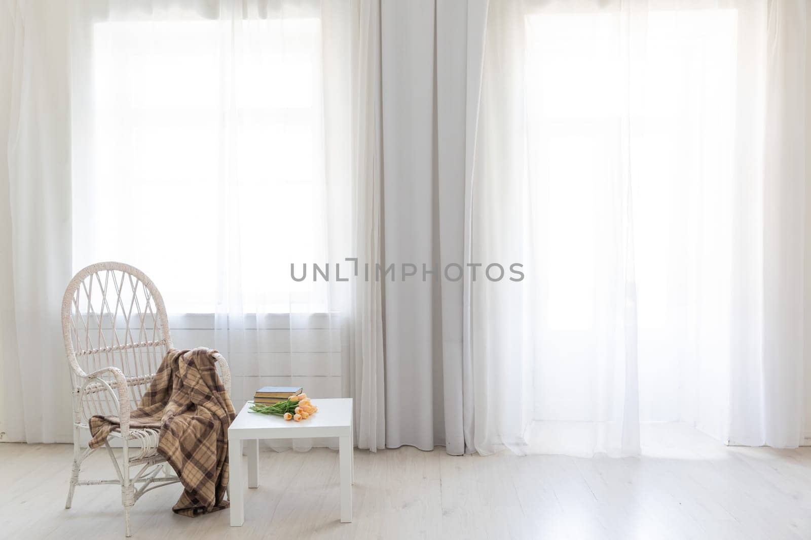 white old chair and table with book in the interior of a room with a window