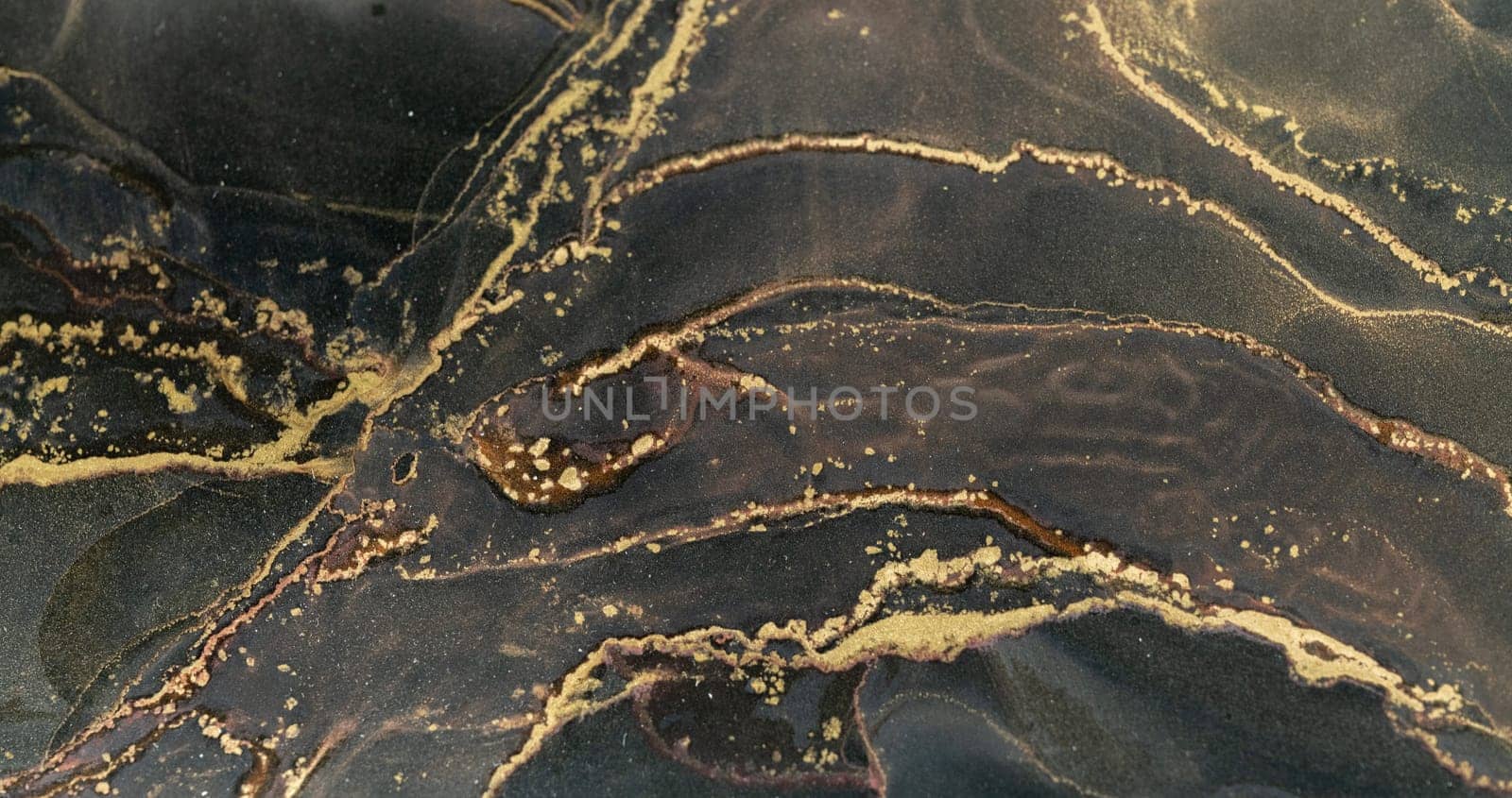 Colorful abstract patterns emerge on a dark surface, showcasing the beautiful flow of alcohol ink.