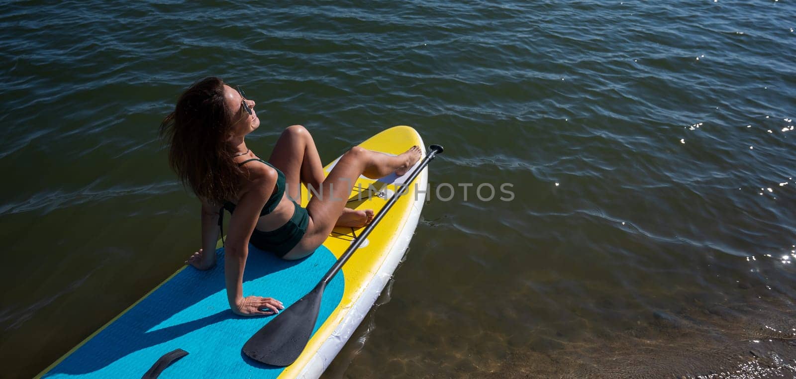 Beautiful caucasian woman is swimming on a SUP board