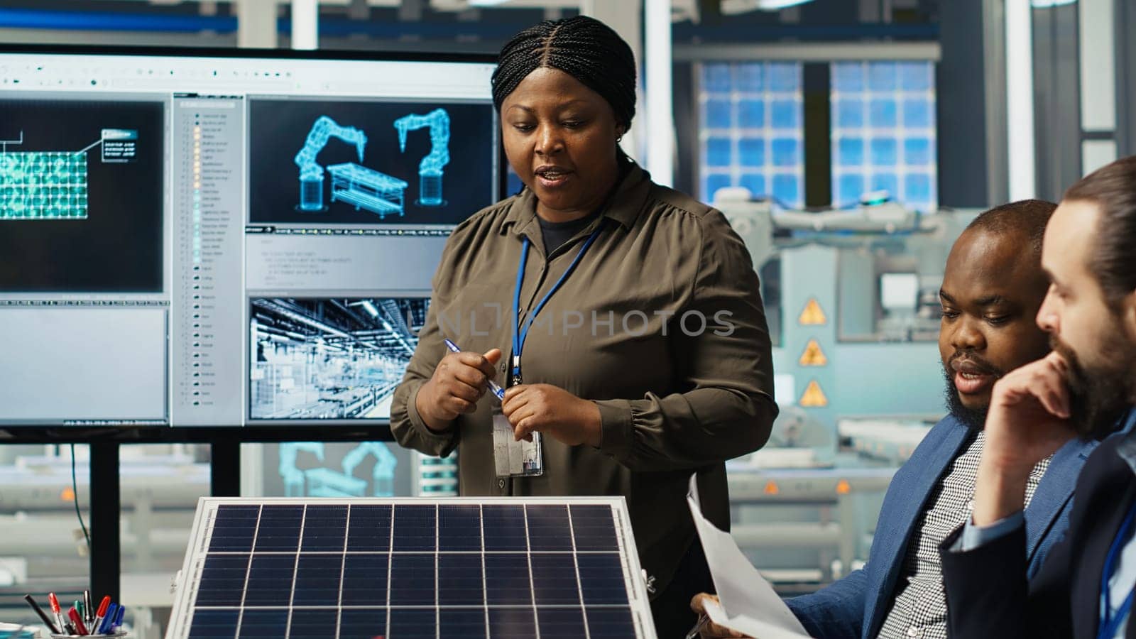Shareholders discussing future investment opportunities in sustainable energy manufacturing. Management executives and investors in solar panels plant reviewing solar technology reports, camera B