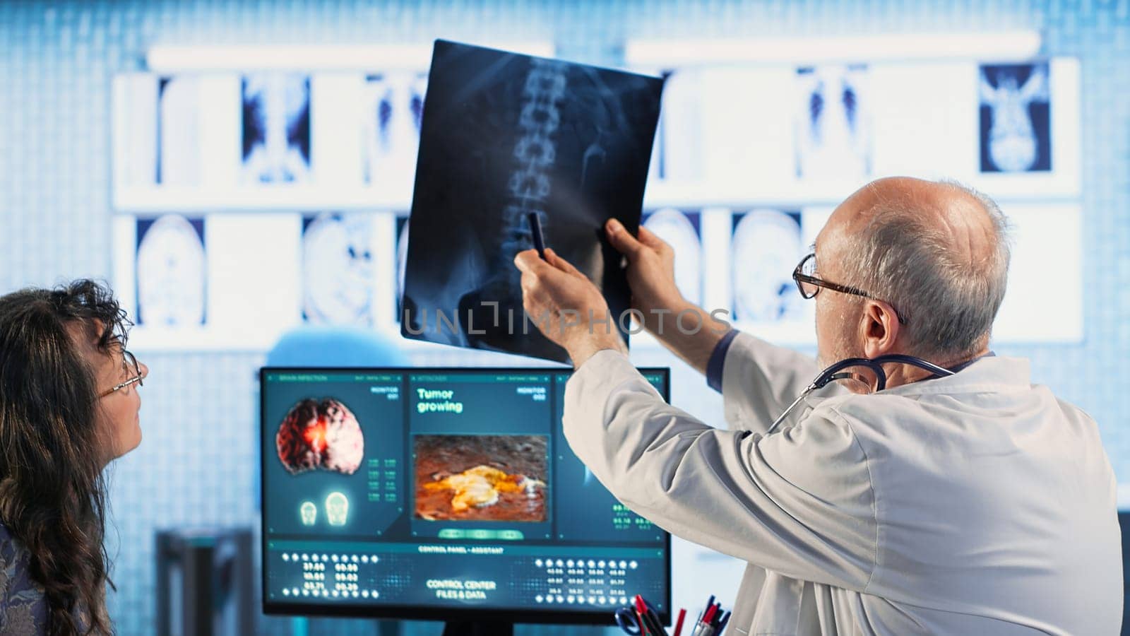 Skilled radiologist uses medical imaging technology to assess cancer risk factors, guiding old female patient through early detection and treatment options. Preventative medicine. Camera B.
