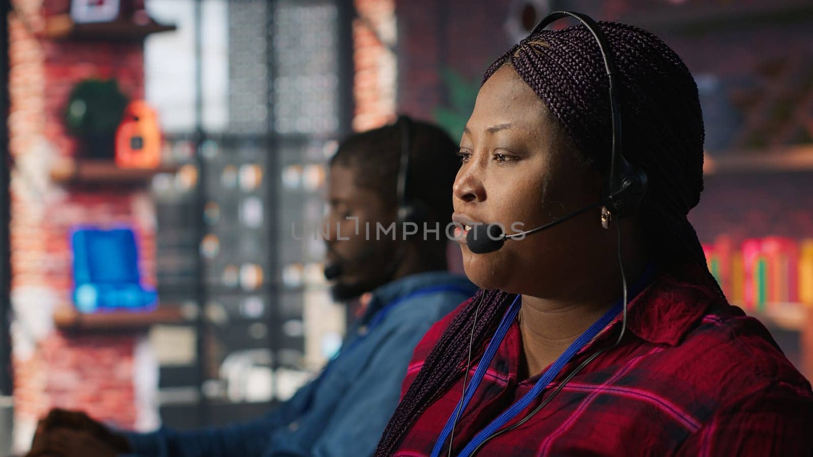 Call center agent listening to customer needs, providing step by step guidance. Customer center worker manages incoming and outgoing calls, walking clients through technical solutions, camera A