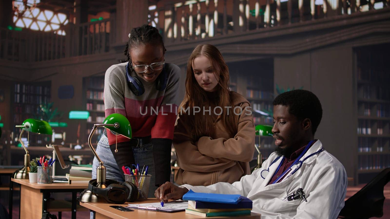 Multiethnic group of students in a library participate at a lesson with doctor, using medical books and materials to gain expertise in pharmacology and microbiology. Scientific studies. Camera B.