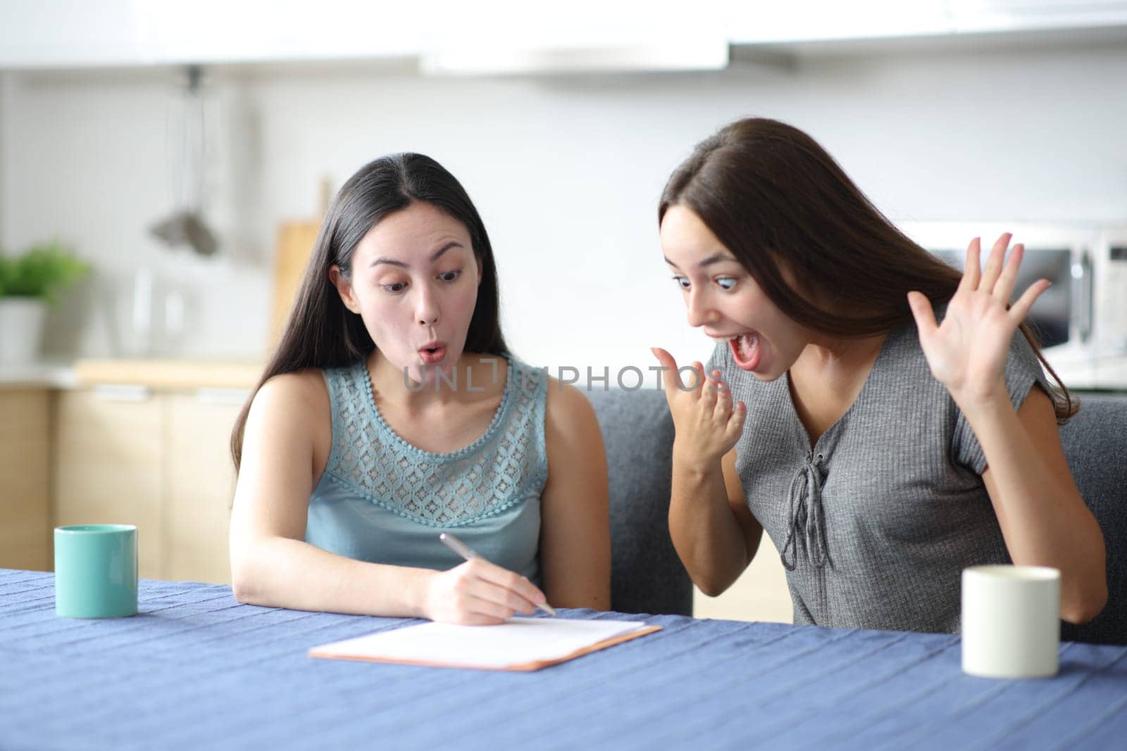 Amazed interracial women checking contract in the kitchan at home