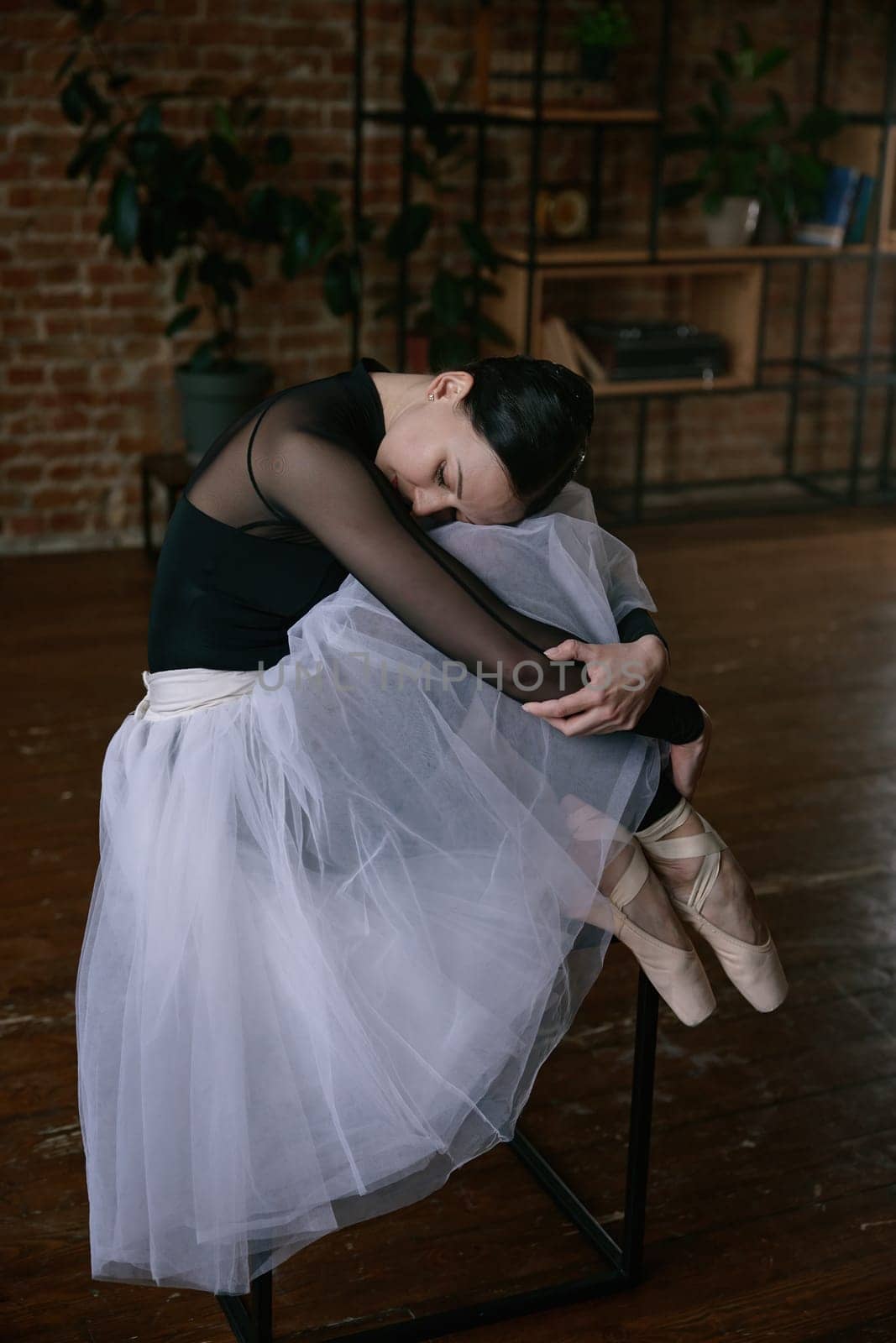 A ballerina gracefully stretches in a minimalist studio, embodying elegance and commitment to her craft