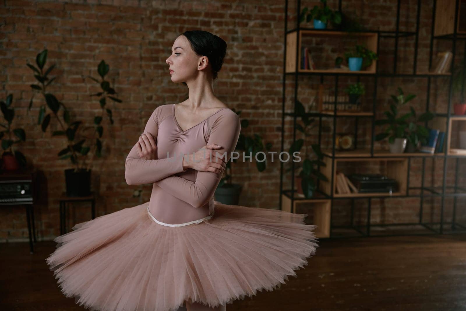 Ballerina is showcasing her exceptional grace while wearing a soft peach tutu in a modern studio space